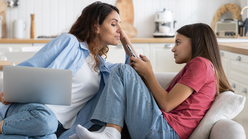 mamma e figlia usano Pc e Smartphone sul divano